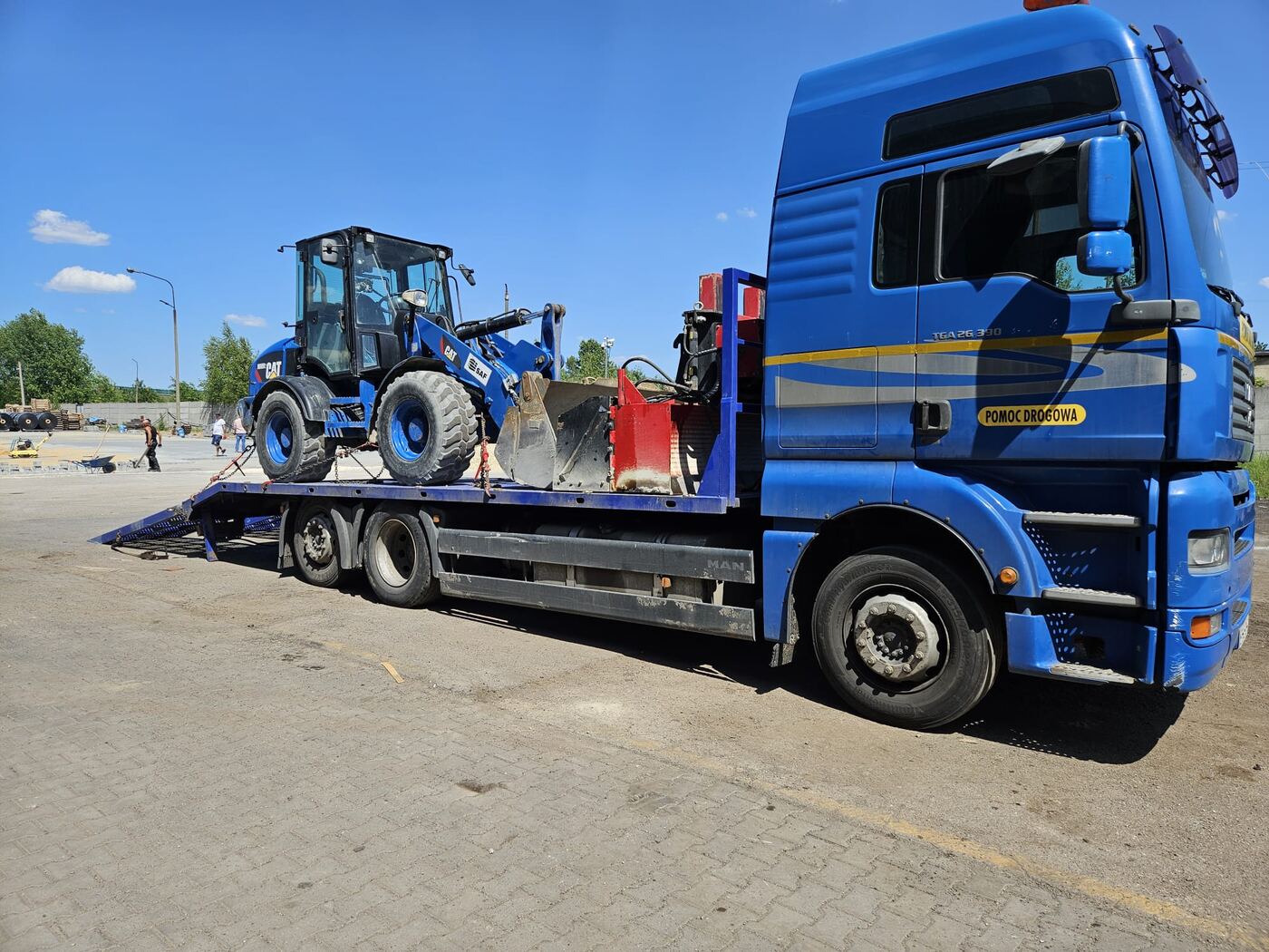 Ładowarka kołowa CAT przewożona na lawecie MAN TGA